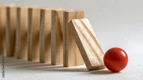 Line of wooden blocks leaning on a red sphere against a light background