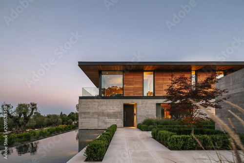 Modern luxury home with pool and garden at dusk