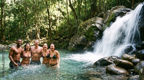 Medium close up of people in swimwear refreshing at forest waterfall mockup
