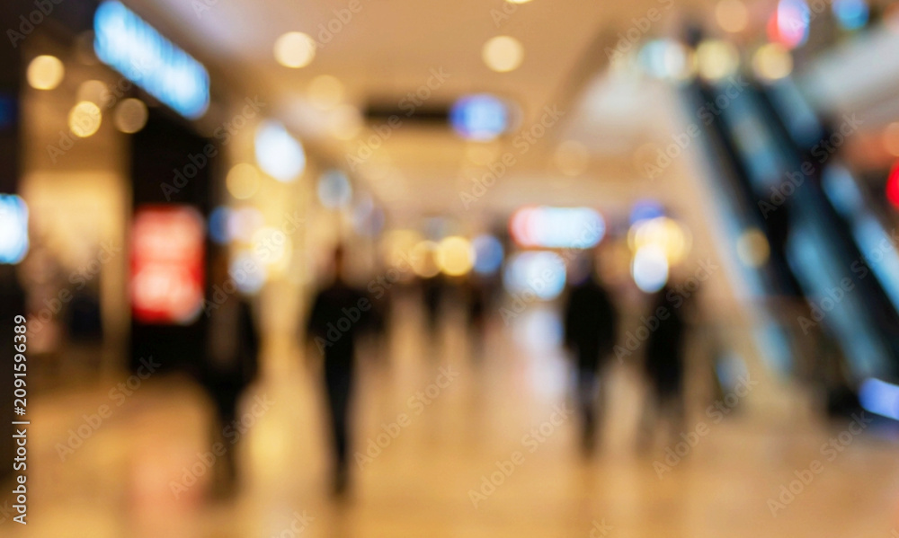 Obraz premium A blurred image of a shopping mall interior with people walking. The soft focus creates a sense of movement and atmosphere in a commercial space.