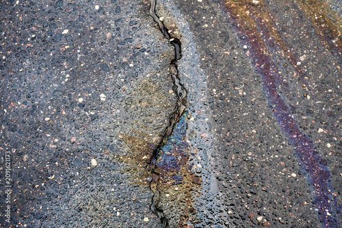 Oil Spill in a Cracked Asphalt Road During Daylight Hours Showing Colors From the Oil.