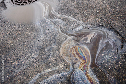 Puddle on the Street Reflects Sunlight as Rainwater Mixes With Oil From Passing Vehicles.