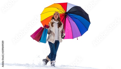 A woman in winter attire smiles while holding shopping bags and a vibrant, rainbow-colored umbrella against a white background