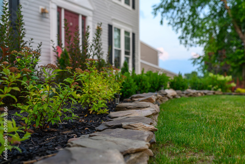 Landscaped Garden Bed with Shrubs and Walkway in Front of a Suburban House