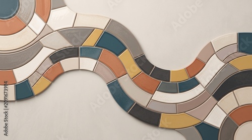 A stunning modern photograph of custom ceramic tiles arranged in a smooth flowing wave pattern, showcasing a beautiful color palette of terracotta orange, teal blue, yellow, grey, and beige.