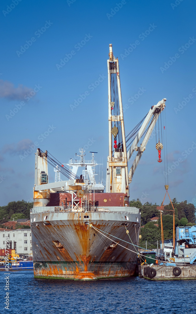 Fototapeta premium A old ship unloading or loading cargo at the port.