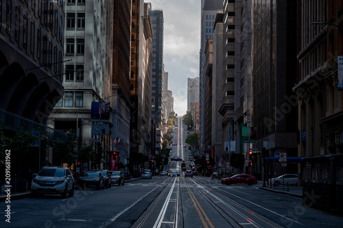 Looking up a steep city street with cable car tracks framed by skyscrapers