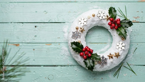 White snowy christmas wreath decorated with holly and silver stars