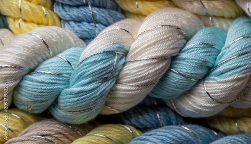 Close-up of thick yarn, braided with silver thread, in soft pastel colors of blue, cream, and yellow.
