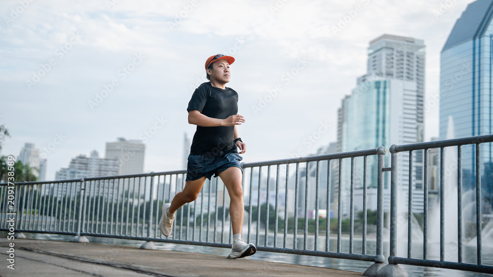 Obraz premium Adult asian athlete man runner training for marathon challenge male wear sports outfit running workout exercise at outdoors urban lifestyle