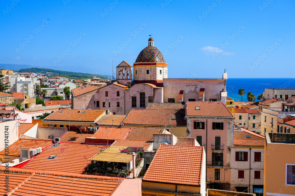 Fototapeta premium Panoramic view of the historic town rooftops and the colorful dome of the Church of Saint Michael the Archangel (Chiesa di San Michele Arcangelo) in Alghero, Sardinia, Italy