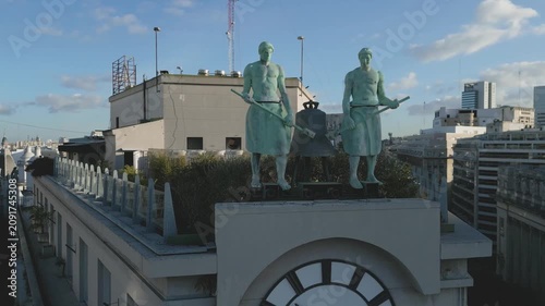 Statues stand on building top in city during clear day