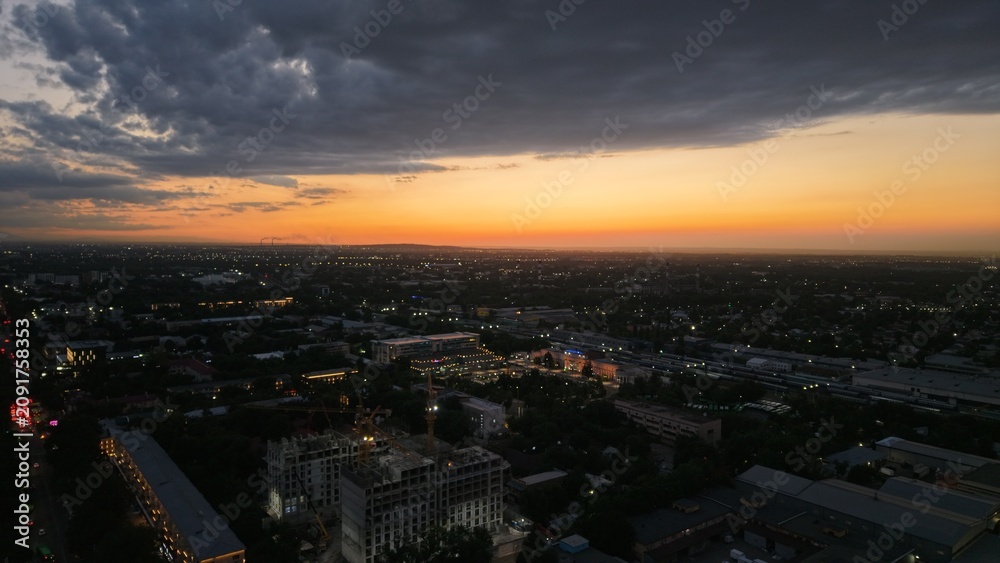 Obraz premium City skyline at sunset with dramatic clouds and urban landscape visible