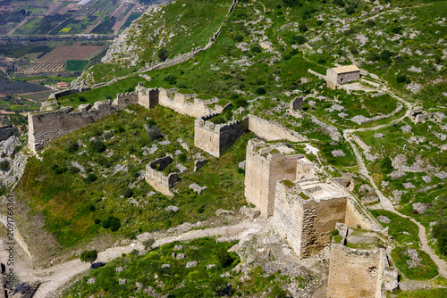 Aerial view of the ancient ruins of Acrocorinth, a fortress overlooking the Corinthian Gulf in Greece, showcasing its extensive walls and towers.