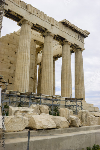 The Parthenon in Athens, Greece, stands majestically with its iconic columns and ancient stonework, surrounded by scaffolding and fallen marble blocks, hinting at ongoing restoration efforts.