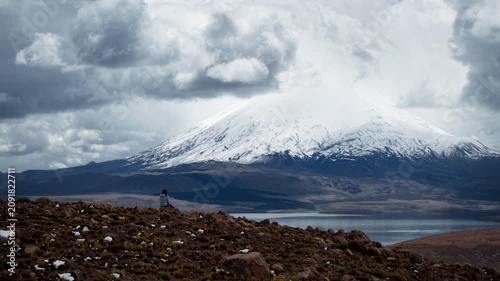 Woman contemplating the Parinacota volcano and Chungara lake. High quality 4k drone footage
