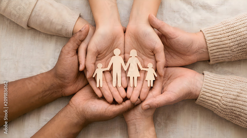 Group of people holding wooden family cutout figures in their hands to show care and protection