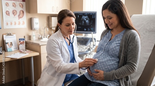 Pregnant woman receiving prenatal checkup from female doctor in clinic