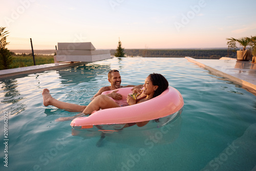 Schilderij op canvas Happy couple having fun in infinity pool during summer holiday.