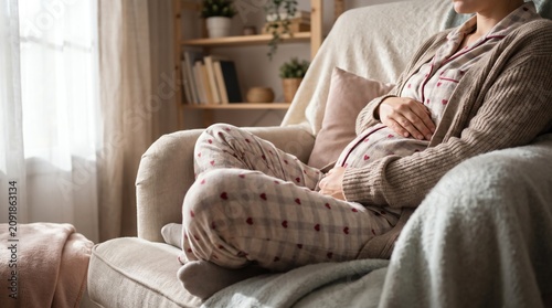 Pregnant woman relaxing on cozy armchair in sunlit living room