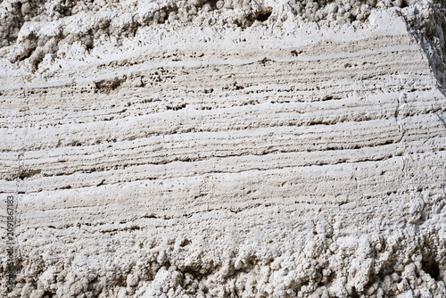 Ancient weathered beige stone surface with deep horizontal erosion and porous edges
