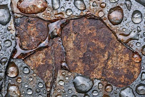 Top view of clear raindrops on wet rusty stone texture