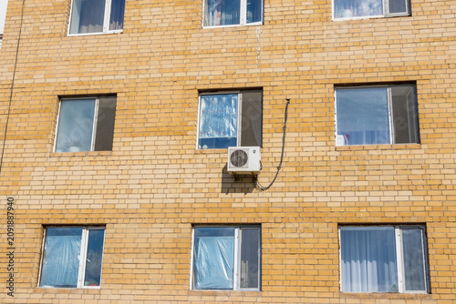 Close-up of an outdoor air conditioning unit mounted on a building wall. HVAC system, climate control, cooling technology, ventilation, energy efficiency and building maintenance concept.
