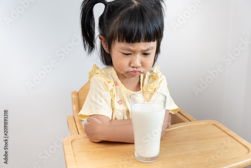 Foto Little girl not like to drink milks, child dislikes drinking milk, refuses, rejection, stop nutrition and growth, calcium, deficiency
