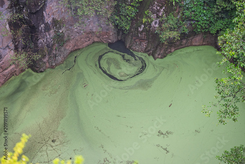 Mount Hypipamee crater with swirling vegetation on the water surface