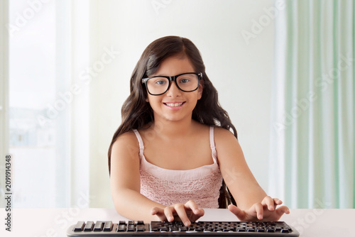 Girl with big black glasses typing on keyboard