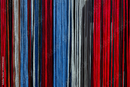 Colorful strands of fabric hang in a textile market in the afternoon sun