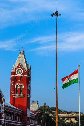 Chennai Central Railway Station clock tower and the Indian flag create a striking composition beneath clear blue skies, reflecting heritage, pride, and timeless beauty.