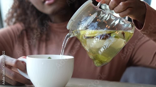 Female hands pour hot fruit tea into a cup in the morning during the cold season
