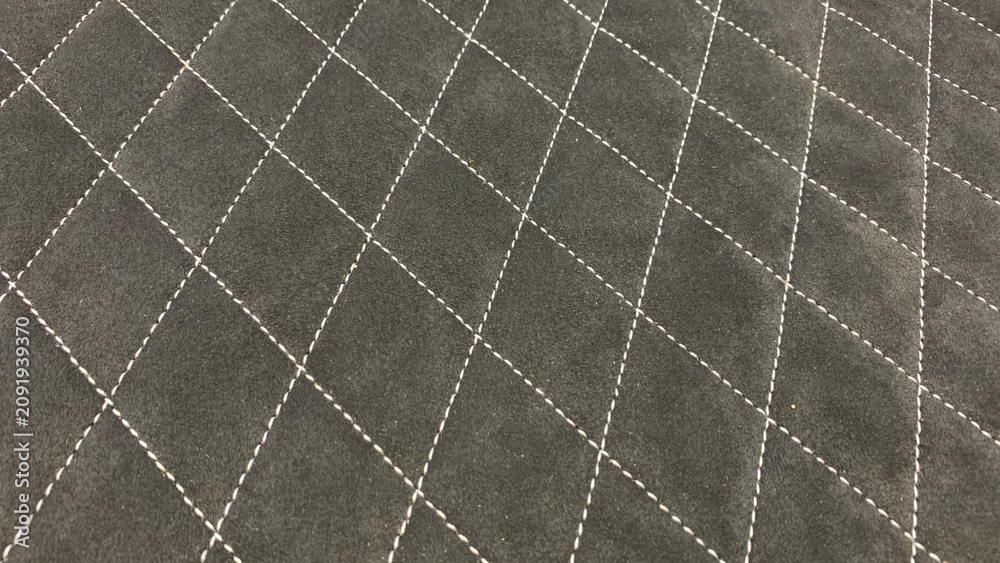 Fototapeta premium Black quilted fabric surface featuring diamond stitching pattern, suitable for upholstery, automotive, and decorative applications