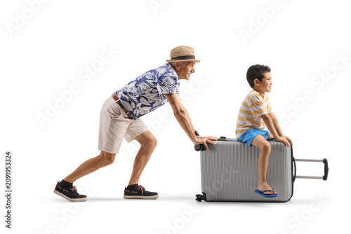 Grandfather pushing a suitcase with his grandson riding on it