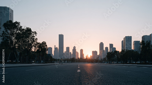 Empty asphalt road city skyline sunrise Empty asphalt road leading toward modern city skyline sunrise, quiet urban street with