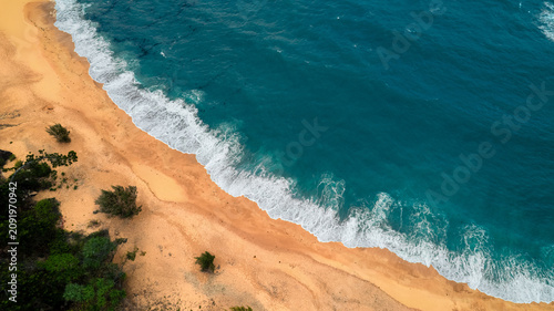 Schilderij op canvas Aerial view of the contrasting turquoise water meeting the sandy beach, while sh