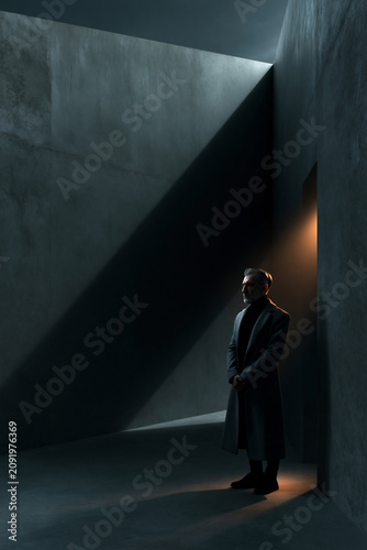 silhouette of person before concrete wall with diagonal shadow, minimalist urban silhouette against concrete architecture and shadow, lonely figure in front of stark concrete wall with dramatic light