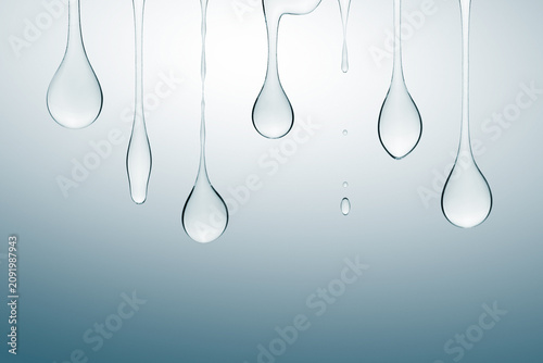 Transparent cosmetic gel dripping down on blue background.