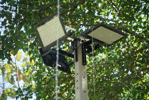 Solar powered led floodlights mounted on pole with green leaves background