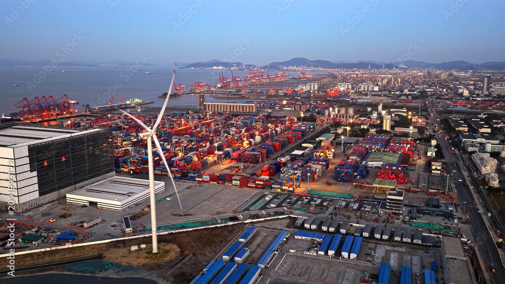 Obraz premium Aerial view industrial port landscape wind turbines. Renewable eco energy facility integration, china infrastructure. Sustainable station development. Chinese shipping containers hub. Windmill harbor.