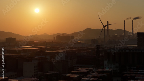 Industrial port area large shipping cargo containers sunset. Fossil fuel power plant air smoke stacks, wind turbine. Global logistics trade industry terminal. Windmill energy factory. Smoking chimneys