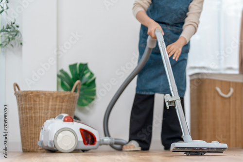 Cleaning vacuum cleaner home floor housework appliance hose person apron cleaning floor at home with canister appliance, hose, basket, plant, tidy room, domestic chore, casual indoor lifestyle