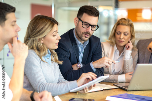 Canvastavla A manager is pointing at a laptop while colleagues are reviewing notes, showing analysis, planning, leadership and collaborative decision making