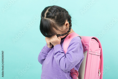Photography An anxious Asian girl is seen fidgeting with her braids, looking down and displaying nervousness – a sign of back-to-school anxiety and childhood stress