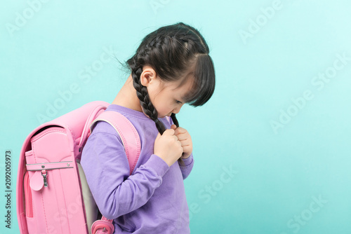 Obraz na plátně An anxious Asian girl is seen fidgeting with her braids, looking down and displaying nervousness – a sign of back-to-school anxiety and childhood stress