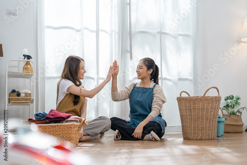 Cuadro en lienzo Woman friend laundry basket home high five two cheerful woman sorting clothing o