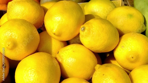 Fresh ripe lemons displayed at local farmers market under bright summer sunlight, vibrant yellow citrus fruit, healthy seasonal produce for cooking, drinks and everyday nutrition