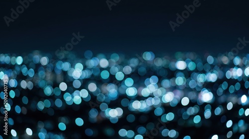 A dense field of blue and teal bokeh circles glows against a dark night sky, evoking distant city lights and creating a cool, abstract urban background.