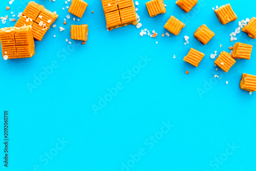 Tableau sur toile Salted caramel pieces - paradoxical sweets - on blue background top view frame c